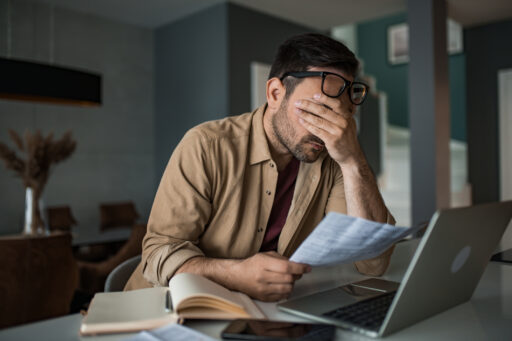 Depressed Young Man Working On Financial Bills At Home.